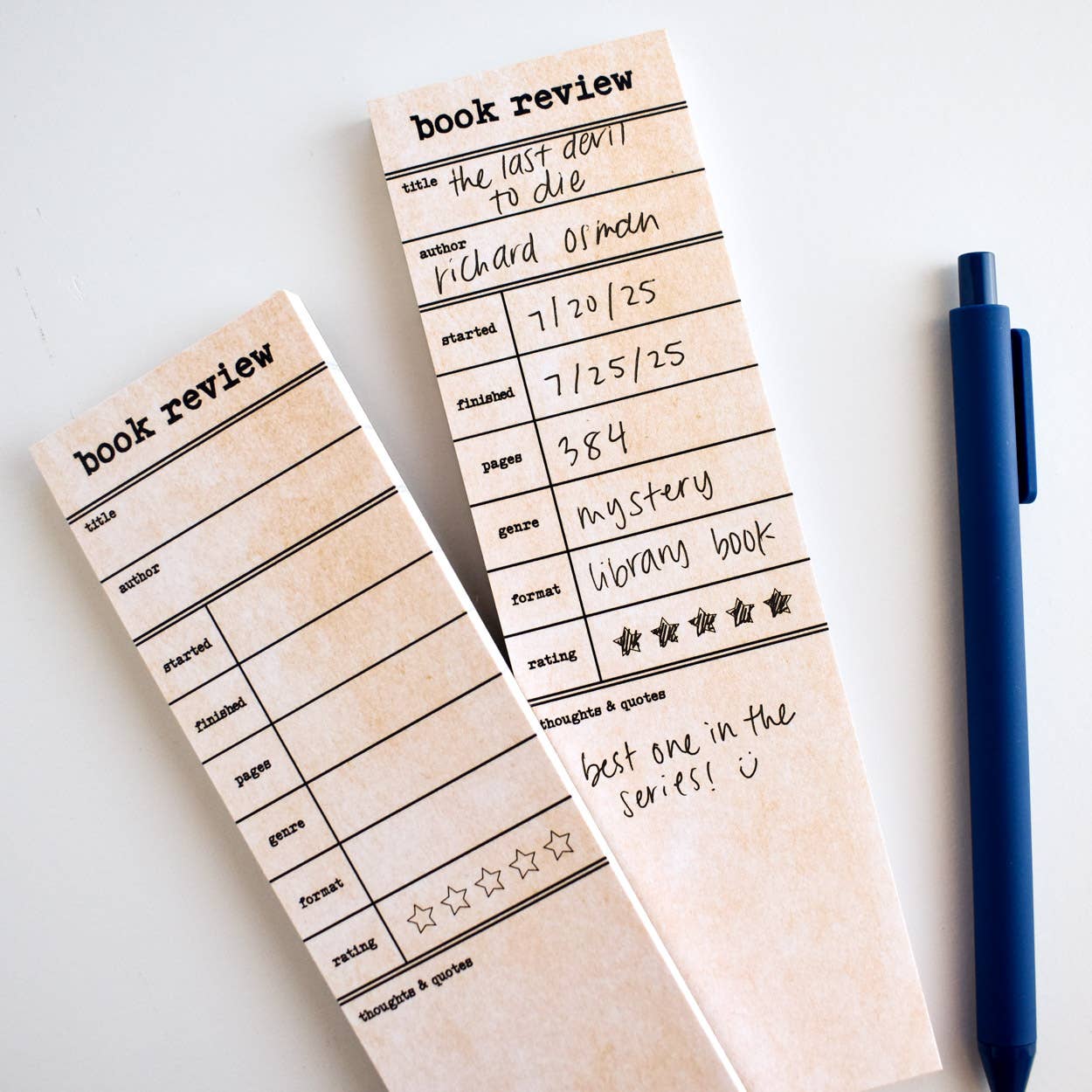 Two book review notepads with a pen on a white background