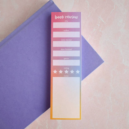 Gradient book review notepad with a yellow and pink design on a textured surface