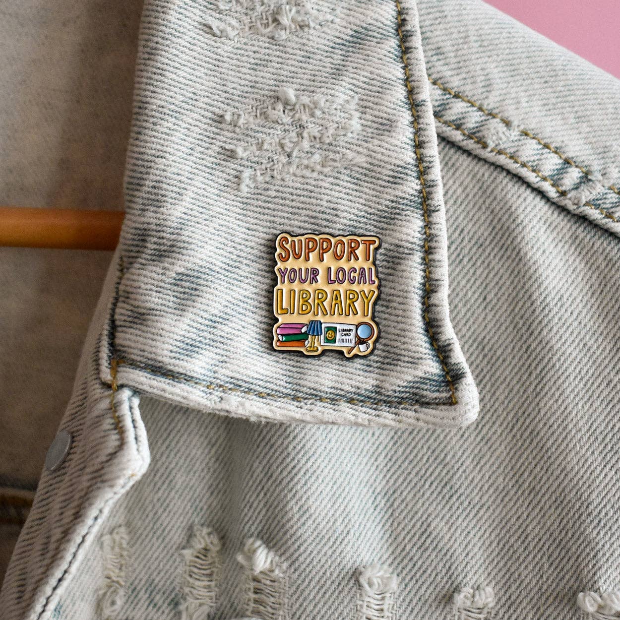 Denim jacket with a 'Support Your Local Library' pin 