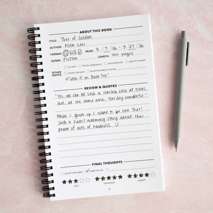 Open reading journal with handwritten book review and rating, pen nearby