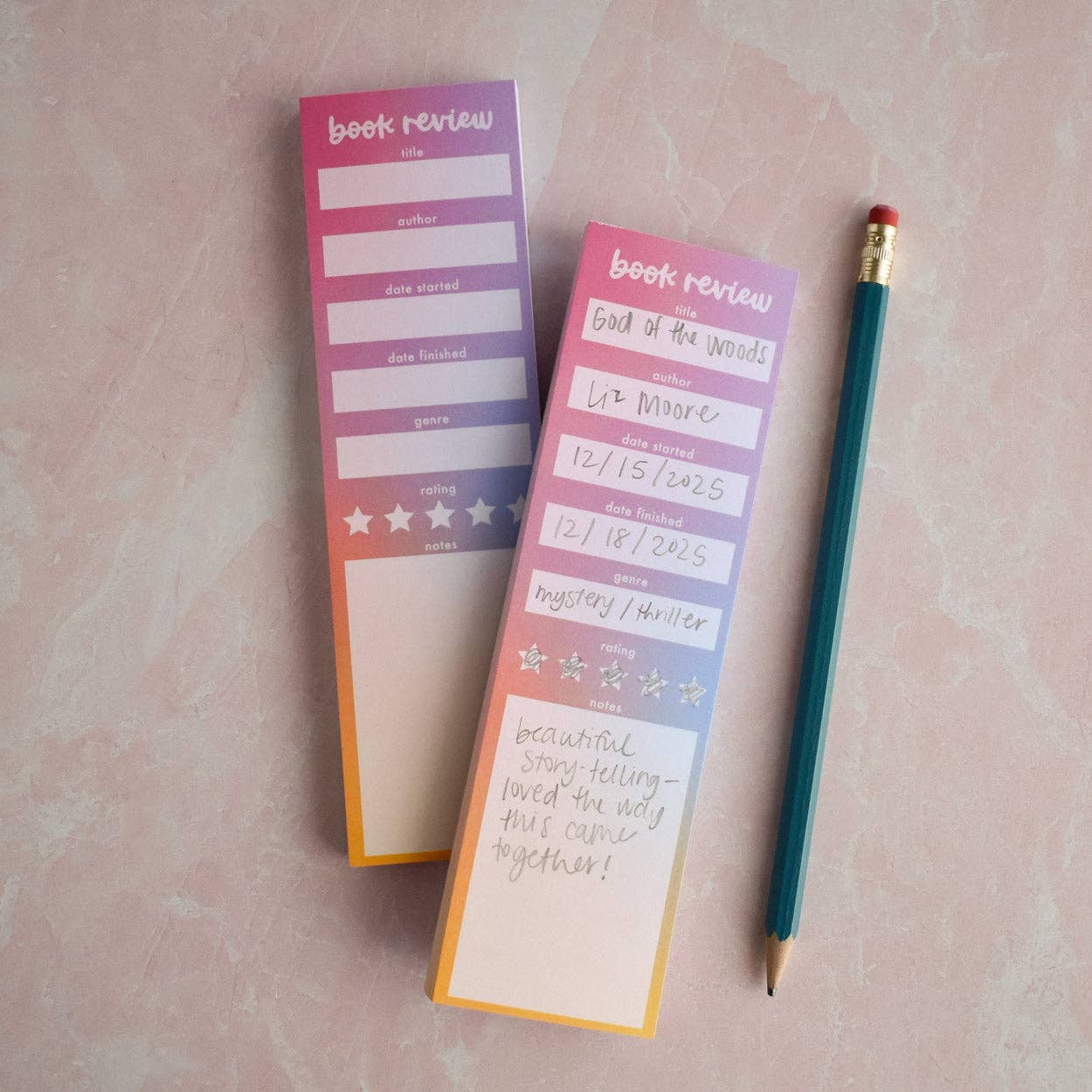 Two book review notepads with a pencil on a pink surface