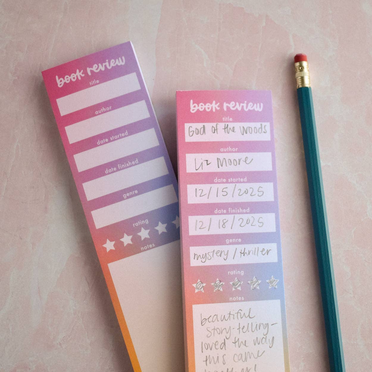 Two book review notepads with a pencil on a pink surface